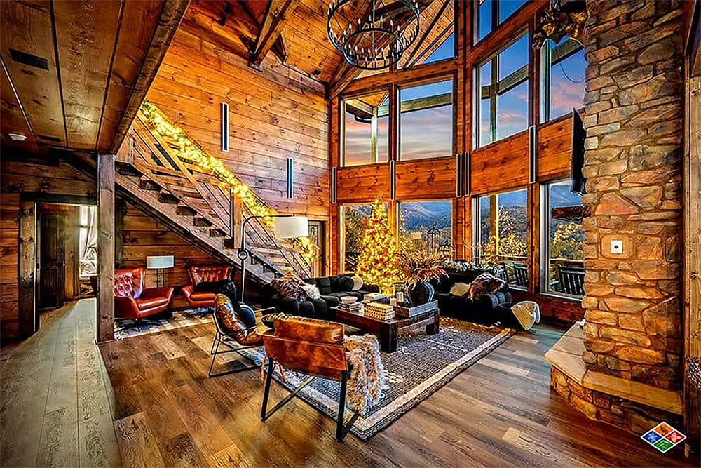 Great room with soaring windows, timber beams, and stone fireplace