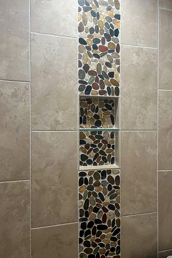 Custom tile floor with decorative pebble mosaic border in a mountain home