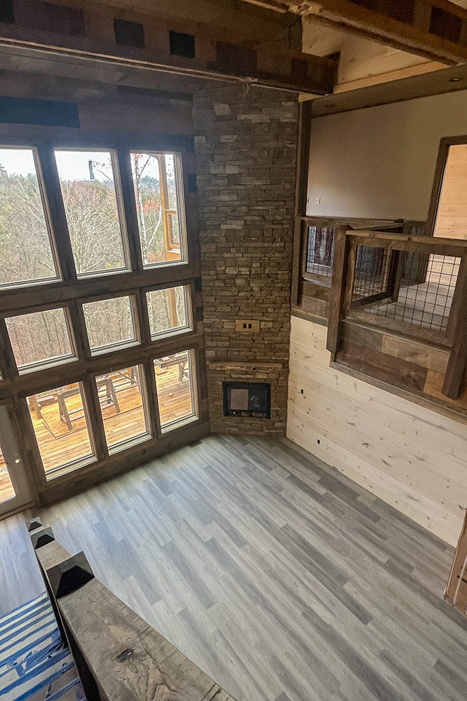 Custom mountain home interior with wood walls, stone fireplace and tall windows
