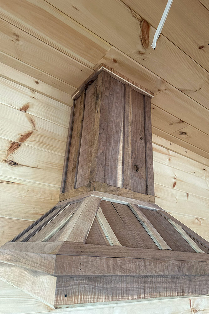 Handcrafted rustic wood range hood installed in a custom cabin kitchen