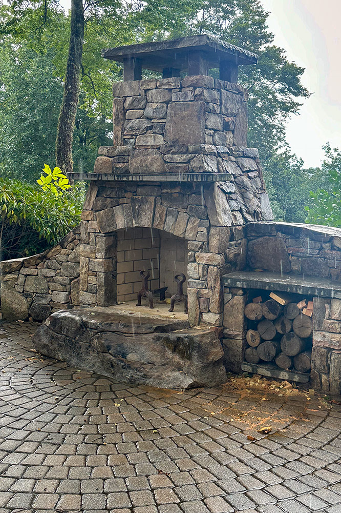 Rustic stone outdoor fireplace beside a custom Smoky Mountain cabin