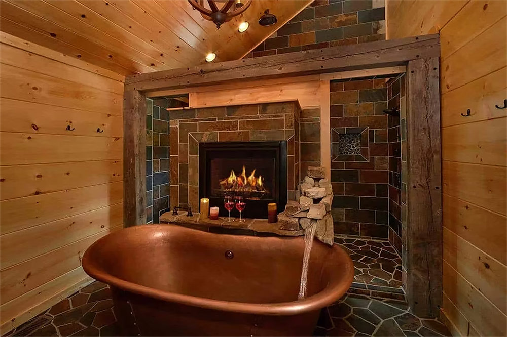 Rustic fireplace with copper soaking tub in luxury cabin bathroom