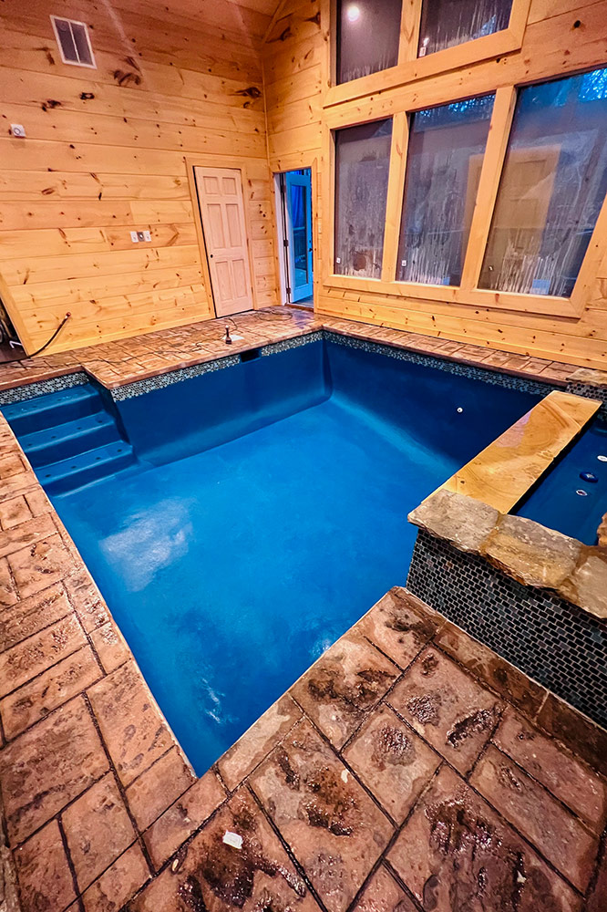 Indoor swimming pool with wood walls and large windows inside a custom cabin