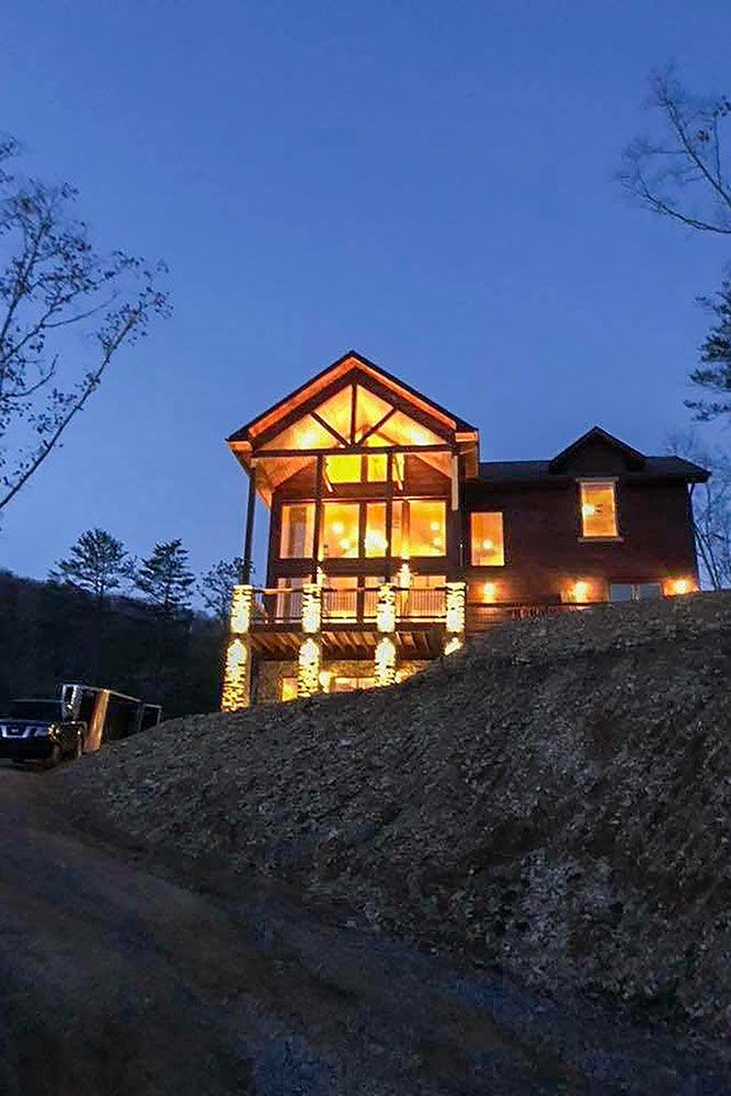 Luxury mountain home illuminated at dusk with expansive floor-to-ceiling windows