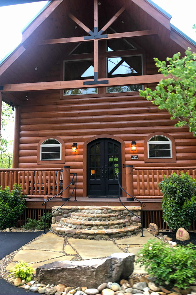 Custom cabin front entrance with log siding, stone steps and timber details