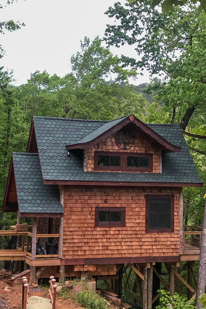 Large custom log cabin with multiple covered decks in a wooded setting