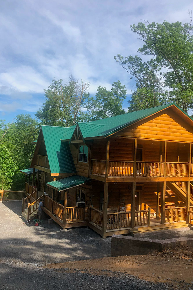 Custom mountain cabin with green metal roof and spacious covered decks