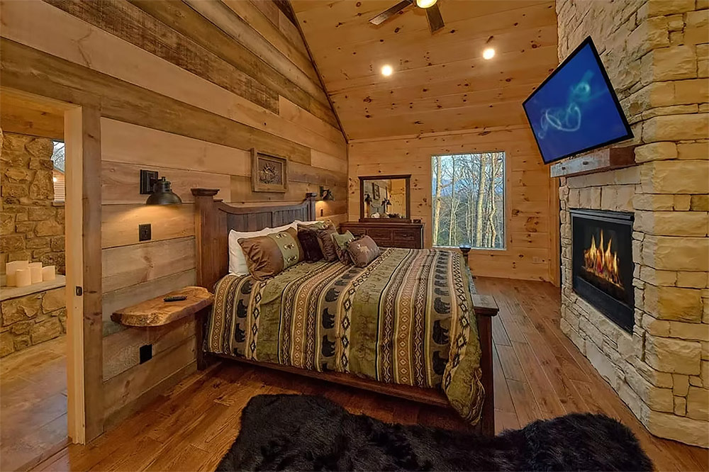 Primary bedroom with stone fireplace and rustic wood interior