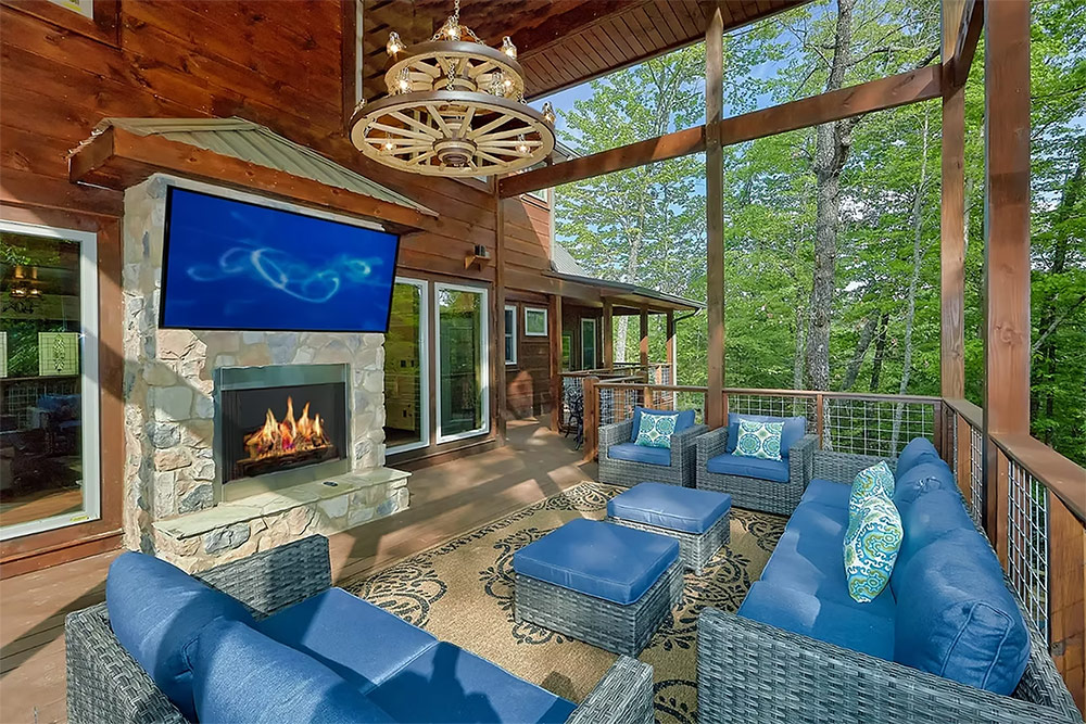 Covered outdoor living room with fireplace and wooded views